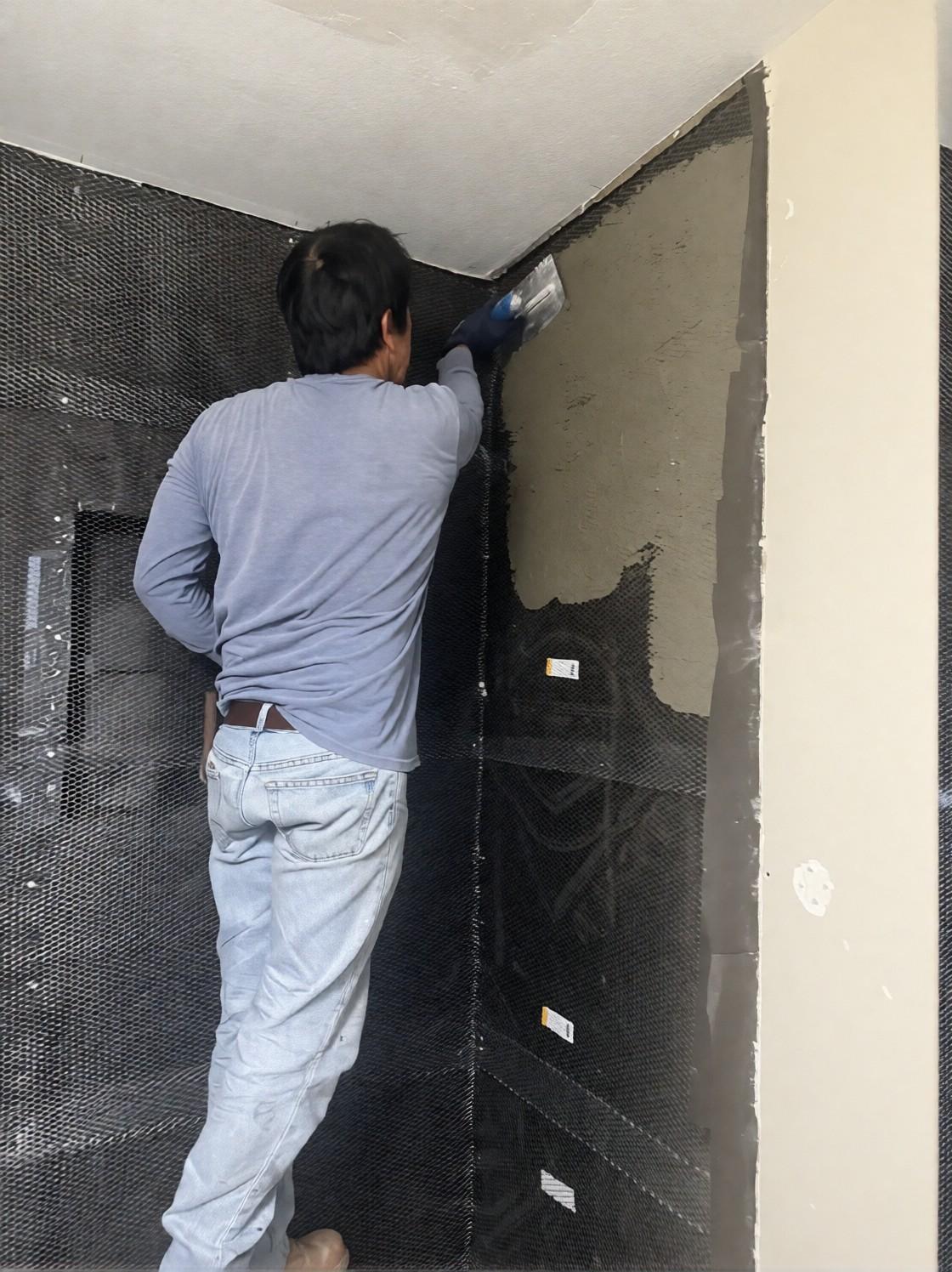 Crew floating mortar over lath on the shower walls