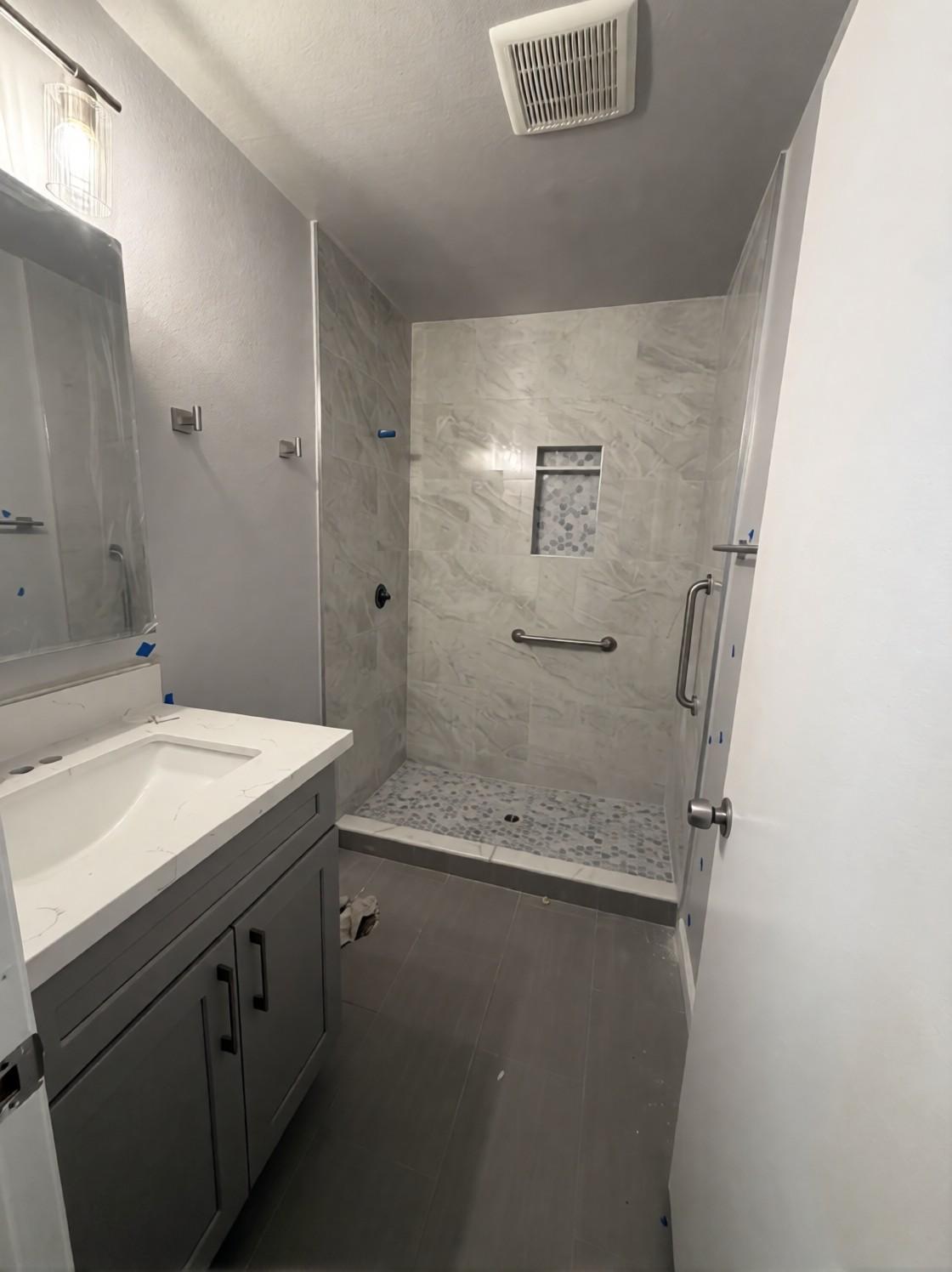 Finished bathroom from the doorway: new vanity, floor tile and shower