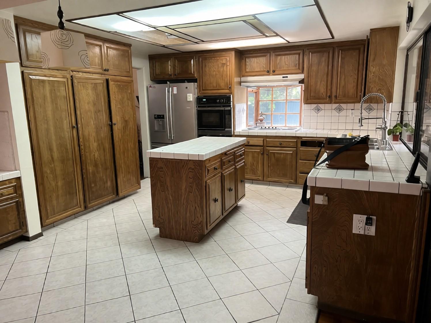 Before: closer view of the old wood cabinets, tile-top island and peninsula